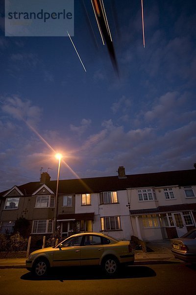 Verschwommene Ansicht des Flugzeugs über Auto vor Haus  London  England
