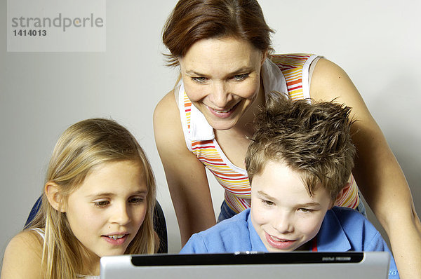 Nahaufnahme Frau betrachten ihre beiden Kinder mit laptop