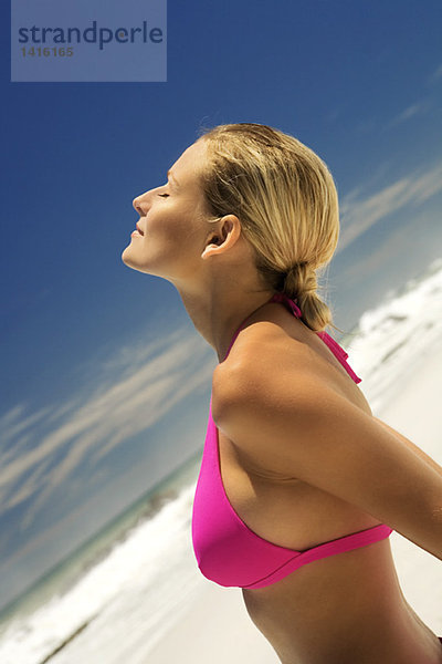 Junge Frau in rosa Bikini am Strand  Kopf zurück  Augen geschlossen