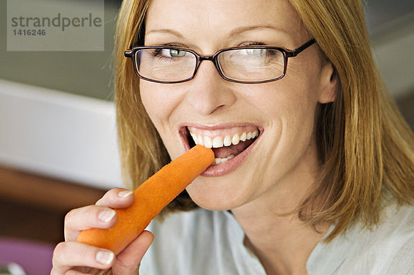 Porträt einer Frau beißt Karotte