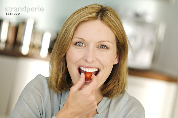 Porträt einer Frau beim Essen von Kirschtomaten