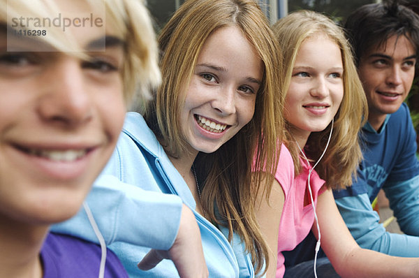 2 Teenager-Jungen und 2 Teenager-Mädchen lächelnd vor der Kamera