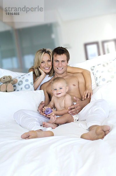 Junges Paar und Baby im Wohnzimmer  Blick in die Kamera  drinnen