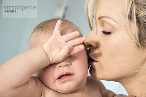 Porträt einer Mutter  die ihr Baby küsst  drinnen