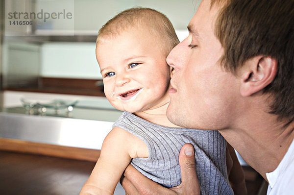 Porträt von Vater und Sohn in der Küche  Mann küsst sein Baby  drinnen