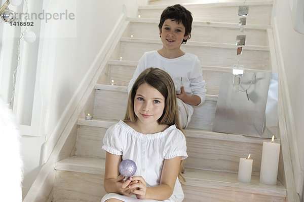 Little girl sitting indoors  holding a Christmas ball
