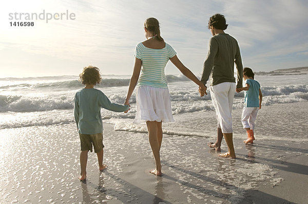 Eltern und zwei Kinder beim Spaziergang am Strand  Rückansicht  im Freien