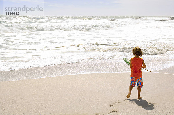 Kleiner Junge am Strand mit einem Kescher  im Freien