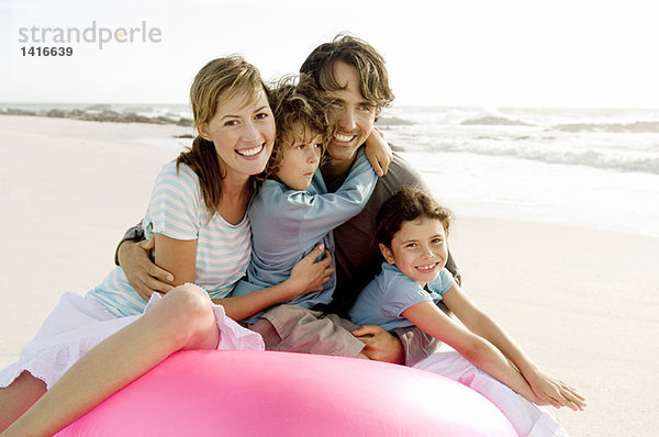 Eltern und zwei Kinder sitzen am Strand  posieren für die Kamera  im Freien