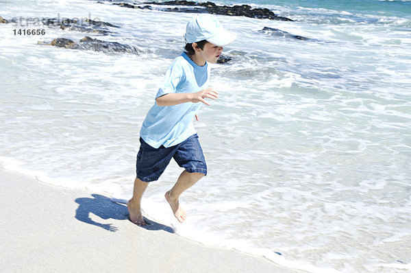 Junge läuft am Strand  im Freien