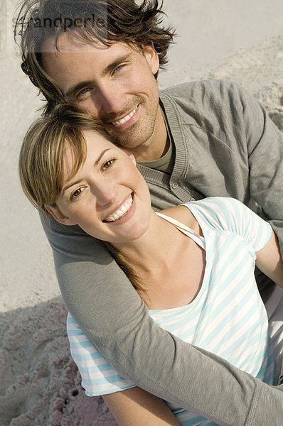 Porträt eines Paares  das am Strand lächelt  für die Kamera posiert  im Freien