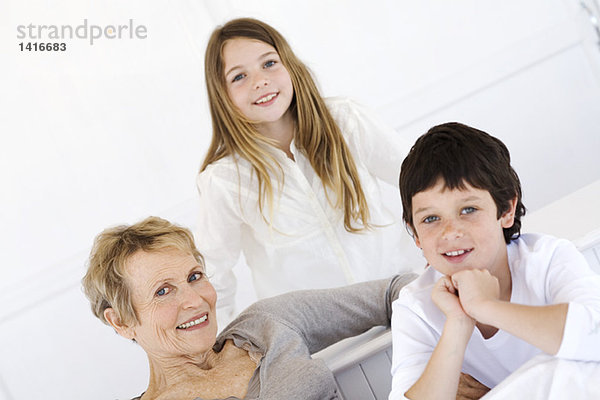 Seniorin und zwei Kinder lächeln für die Kamera  drinnen