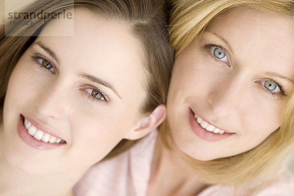 Porträt von zwei Frauen  die für die Kamera lächeln  drinnen