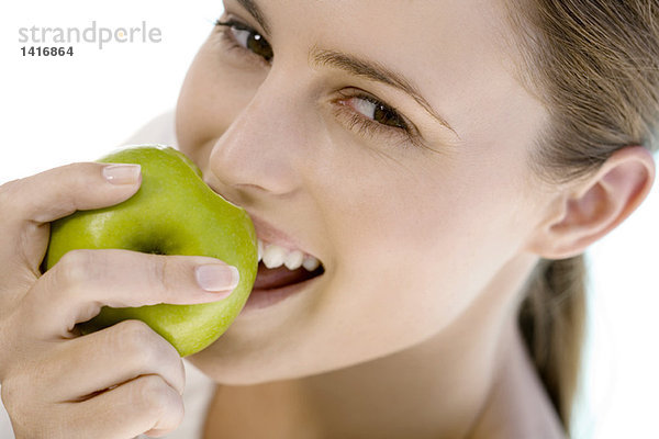 Porträt einer jungen Frau  die einen Apfel isst  drinnen