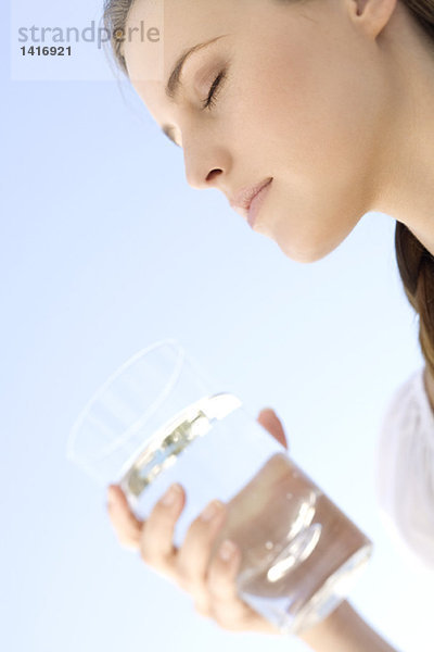 Porträt einer jungen Frau  die ein Wasserglas hält  im Freien