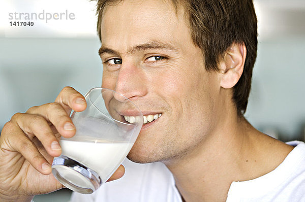 Porträt eines jungen Mannes  der ein Glas Milch trinkt.