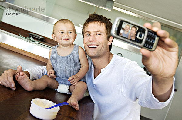 Junger Mann mit Baby  mit Fotohandy