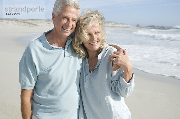 Lächelndes Paar  das sich am Strand umarmt.