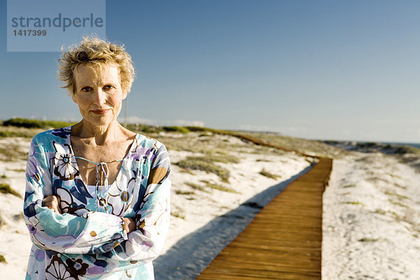 Seniorin mit verschränkten Armen am Meer