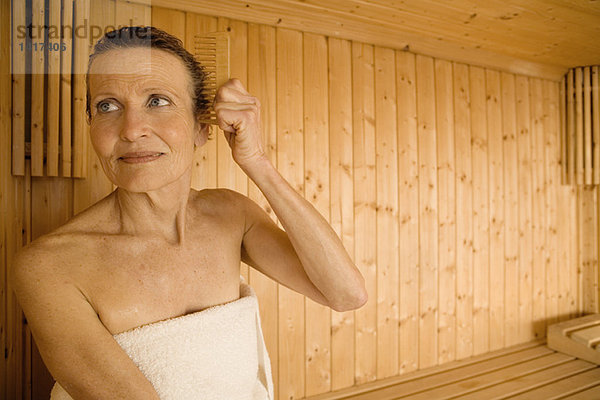 Seniorin kämmt sich in der Sauna die Haare