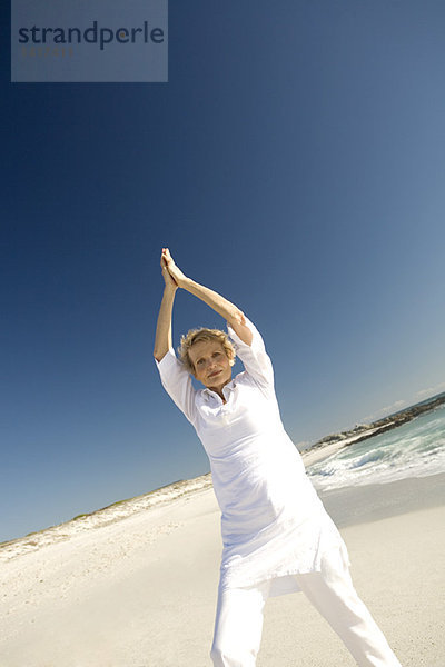 Seniorin beim Yoga am Strand