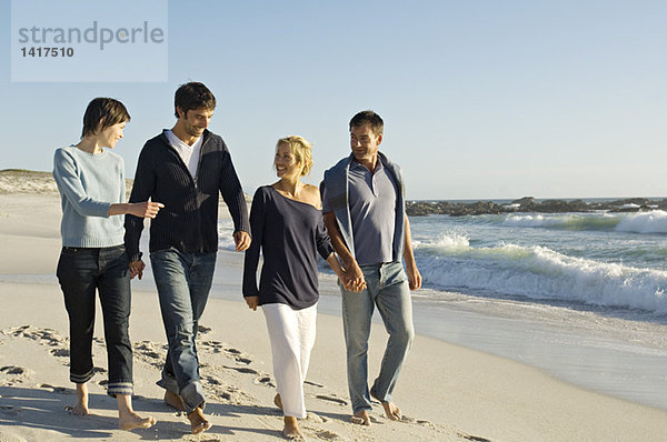 2 Paare  die am Strand spazieren gehen