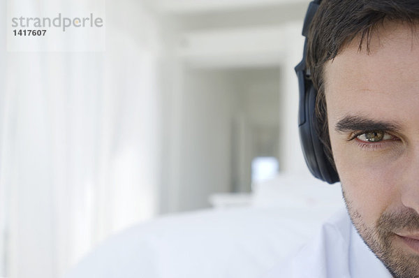 Porträt eines jungen Mannes  der mit Kopfhörern Musik hört.