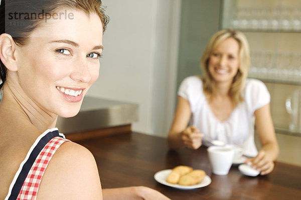 2 lächelnde Frauen am Tisch sitzend