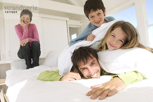Lächelndes Paar und zwei Kinder im Bett