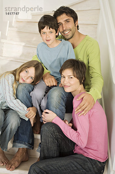 Paar und zwei Kinder lächeln für die Kamera  sitzen auf der Treppe