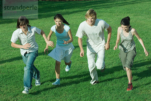 Gruppe junger Freunde  die zusammen über das Gras rennen