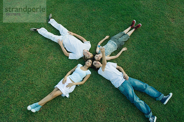 Gruppe junger Freunde  die auf Gras liegen  Köpfe zusammen