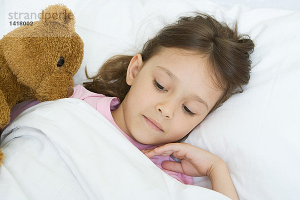 Mädchen im Bett liegend mit Teddybär