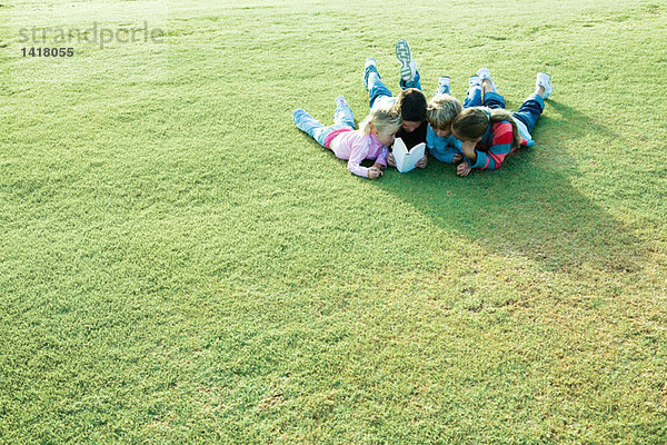 Kinder liegen auf Gras  lesen gemeinsam ein Buch