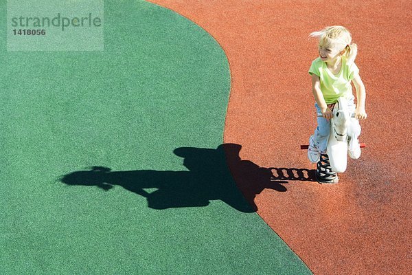 Mädchen auf dem Spielplatz sitzend  Schaukelpferd  Hochwinkelansicht