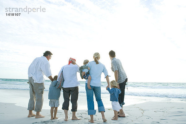 Drei Generationen Familie am Strand stehend