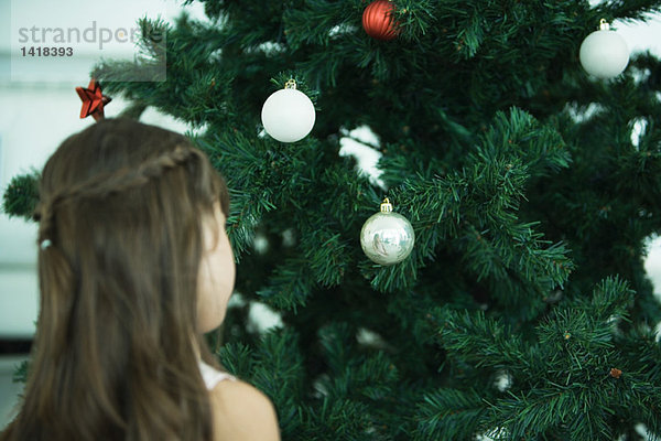 Mädchen schaut auf den Weihnachtsbaum
