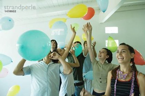 Gruppe junger Freunde  die in der Luft schwebende Luftballons treffen