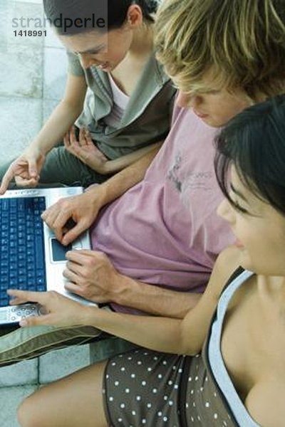 Junge Freunde  die den Laptop zusammen benutzen  hohe Blickwinkel