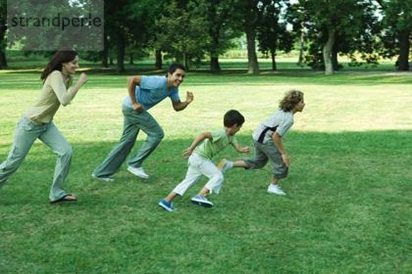 Familie im Freien  gemeinsam über das Gras rennen