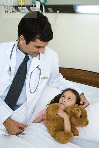 Arzt sitzt neben einem kranken Kind