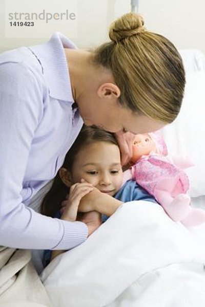 Frau hält Hände mit Tochter im Krankenhausbett