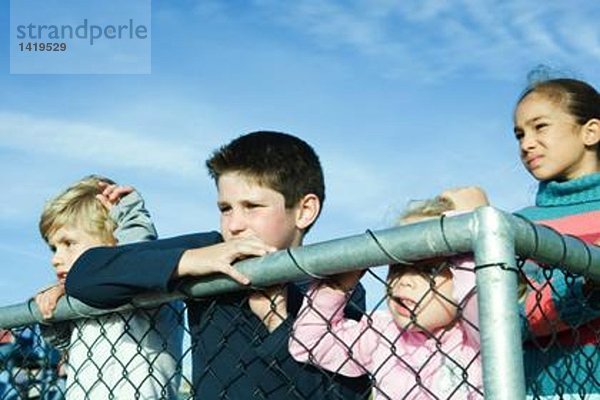 Kinder stehen hinter dem Zaun