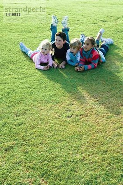 Kinder  die zusammen auf Gras liegen