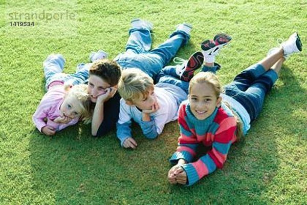 Kinder  die zusammen auf Gras liegen