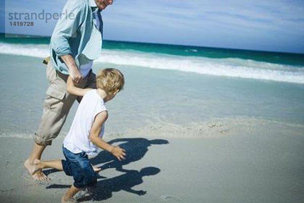 Mann und Junge gehen am Strand spazieren