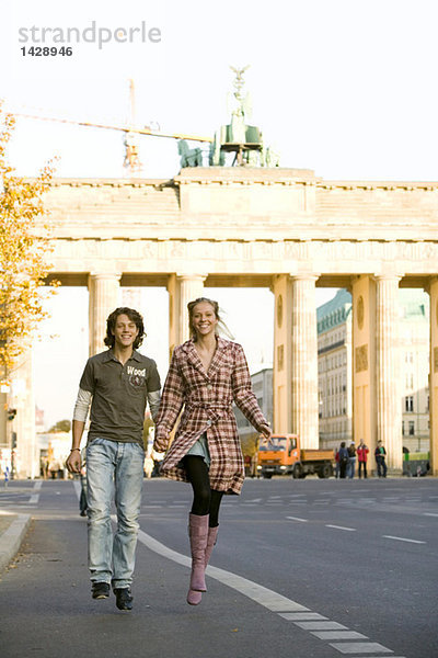 Junges Paar läuft auf der Straße  Hand in Hand