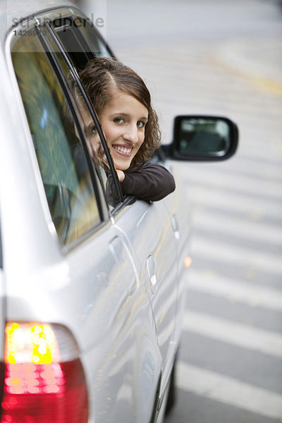 Junge Frau  die aus dem Auto schaut  lächelnd