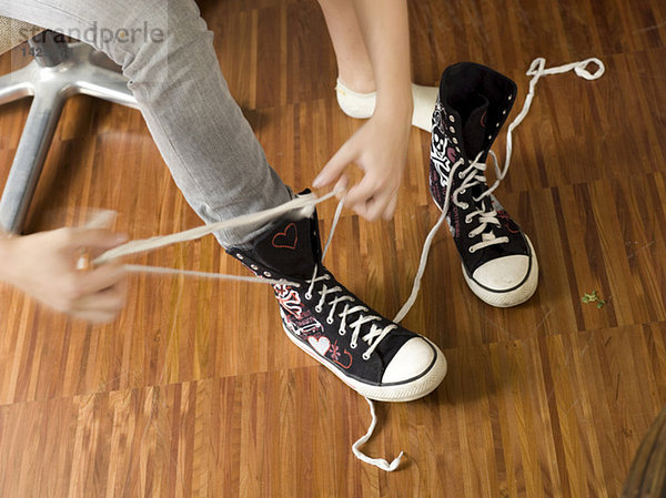 Junge Frau bindet Schuhe  Detail