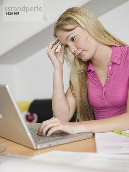 Junge Frau auf dem Schreibtisch sitzend  mit Laptop